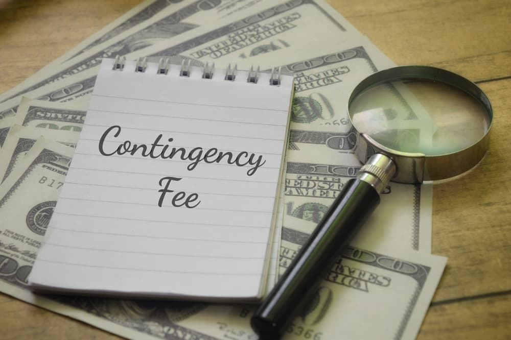 Magnifying glass focusing on 'Contingency Fee' text with money in the background, representing a business concept.