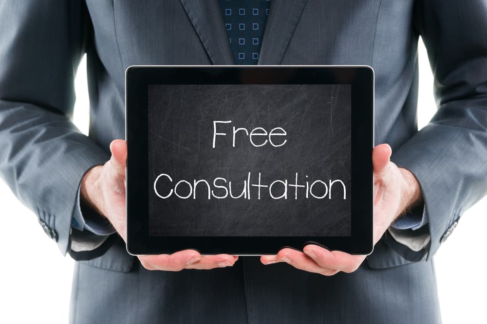 Businessman holding tablet with 'FREE CONSULTATION' displayed on a chalkboard screen.