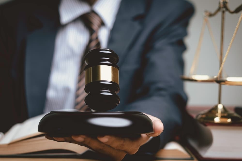 Lawyer's hand with judge gavel, businessman in suit, representing digital legal services: justice, prosecution, legal advice, lawsuit, and investigation.