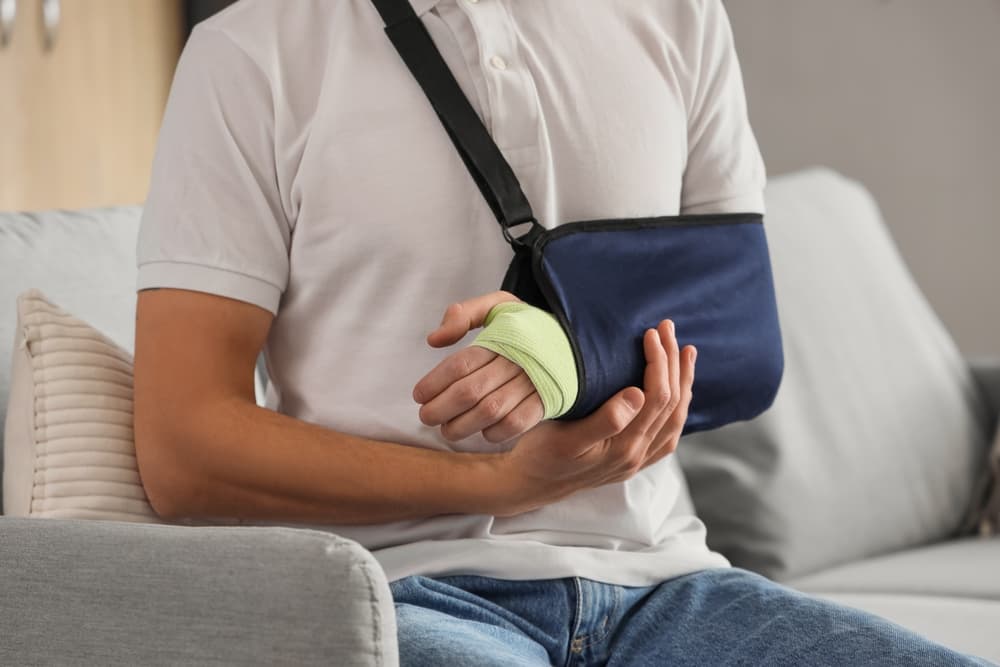 Close-up of an injured young man sitting on a sofa at home after an accident.