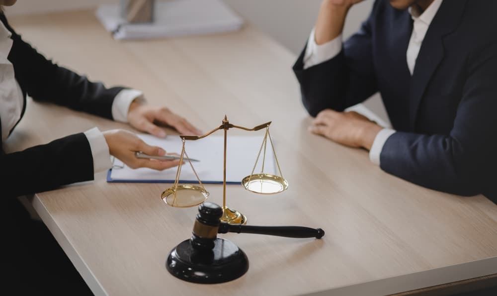 Businessman and woman lawyers working together with law book at desk in office, representing justice and legal consultation.