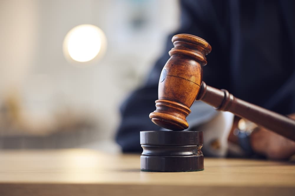 Lawyer's hand with gavel, symbolizing justice during a court hearing and legal trial. Close-up of desk, representing investigation, criminal case, and verdict order.