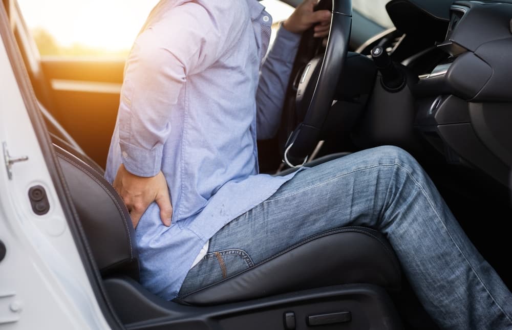 Close-up of a man experiencing severe back pain after a long drive.