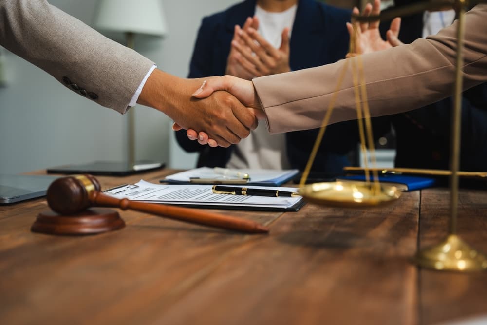 Middle-aged partner lawyers shaking hands after finalizing a contract agreement.