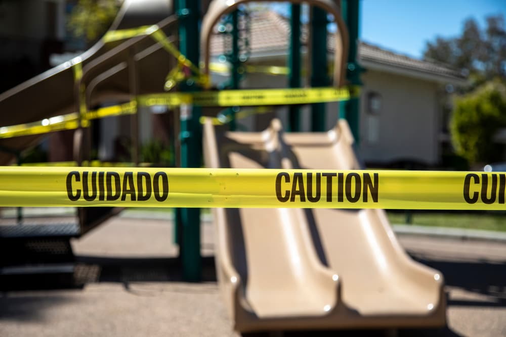 Playground slide cordoned off with caution tape, indicating a potential hazard.