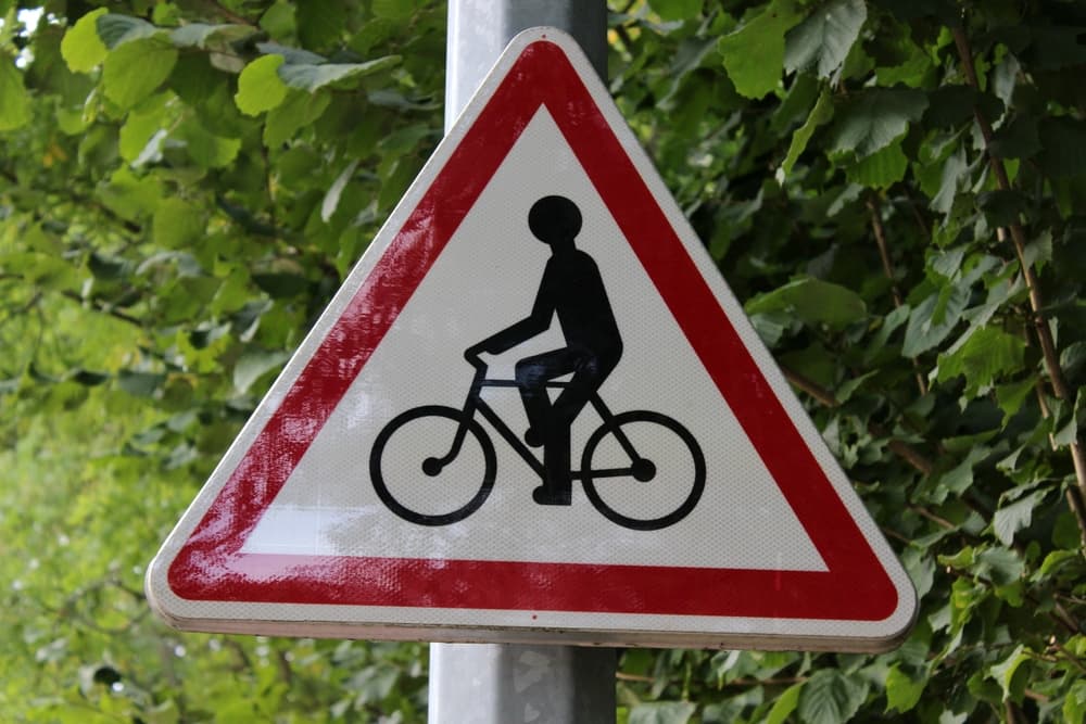 A triangular road sign with a bicycle symbol warns of cyclists ahead.