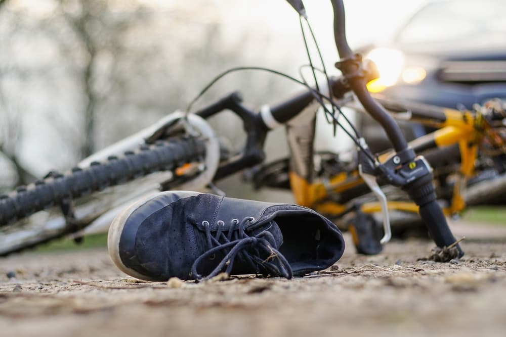 A bicycle accident scene with a lone shoe and a bike on the ground.