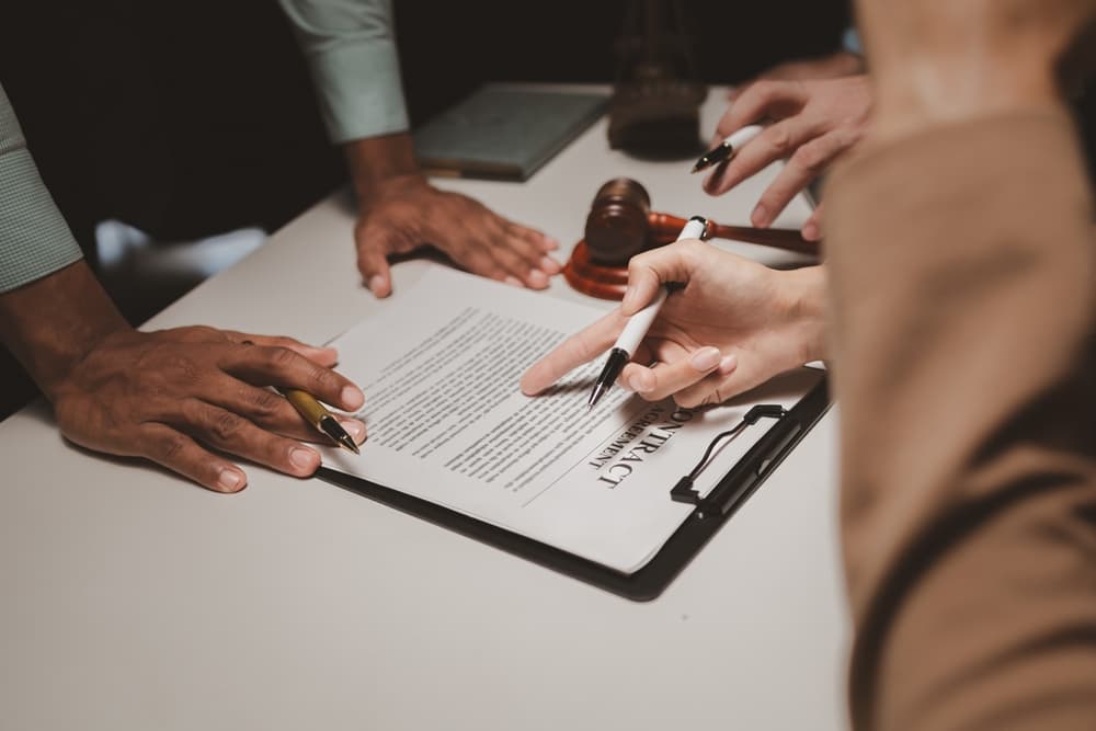 A group of lawyers is discussing contract documents that must be presented to a client