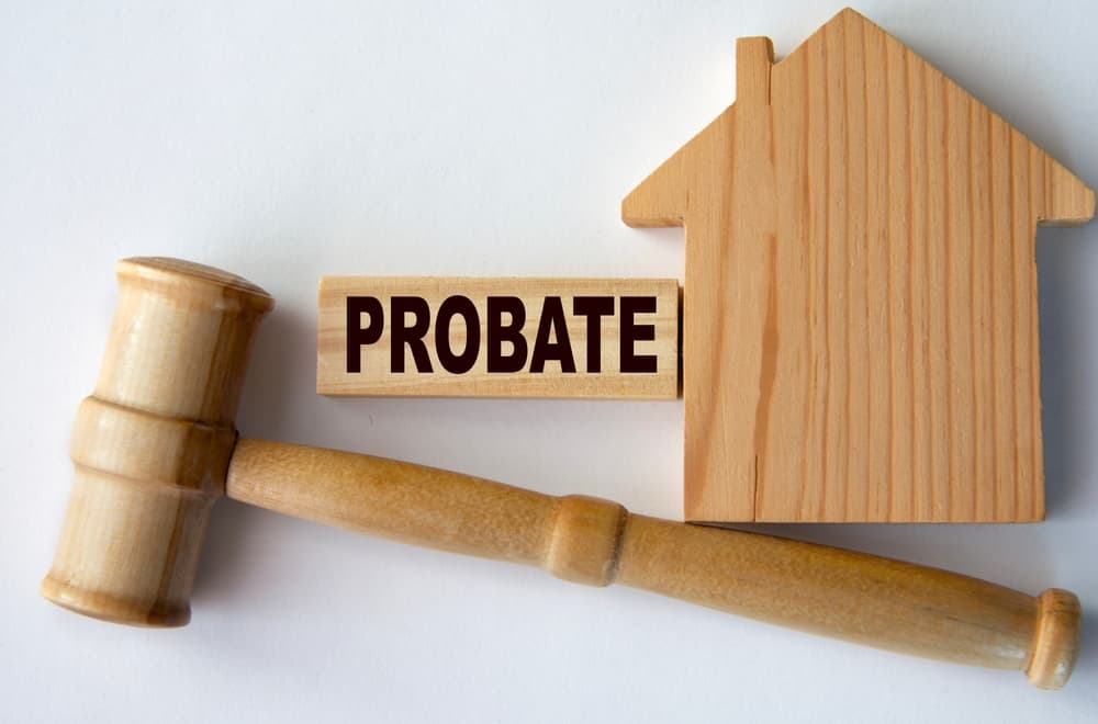 A wooden gavel, block labeled "Probate," and a house model symbolize the legal probate process.