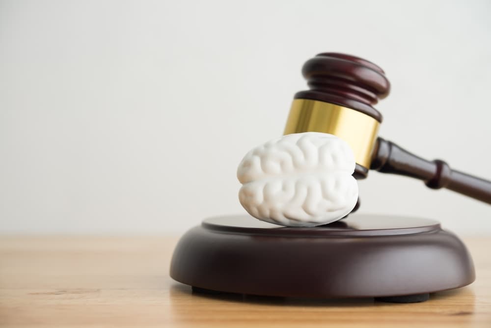 Brain and hammer judge gavel on wooden table in courtroom with white wall background copy space.