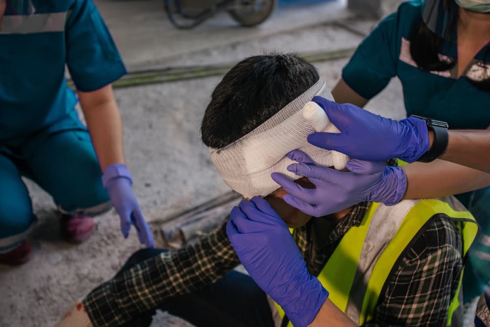 Paramedic first aid bandaging head to a man builder accident fall scaffolding to the floor at construction site.