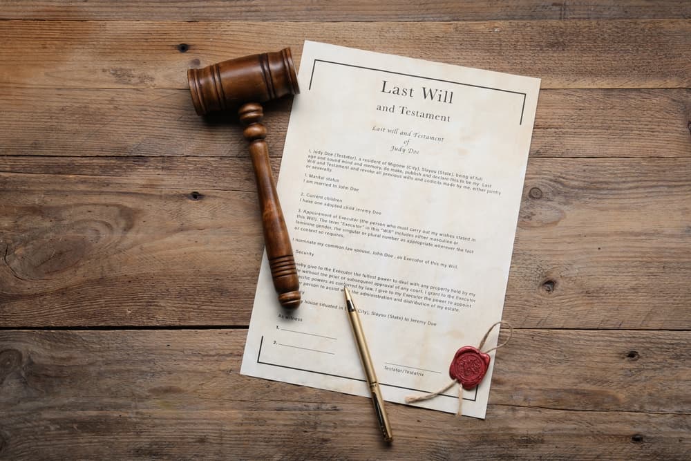 Last Will and Testament with wax seal, gavel and pen on wooden table